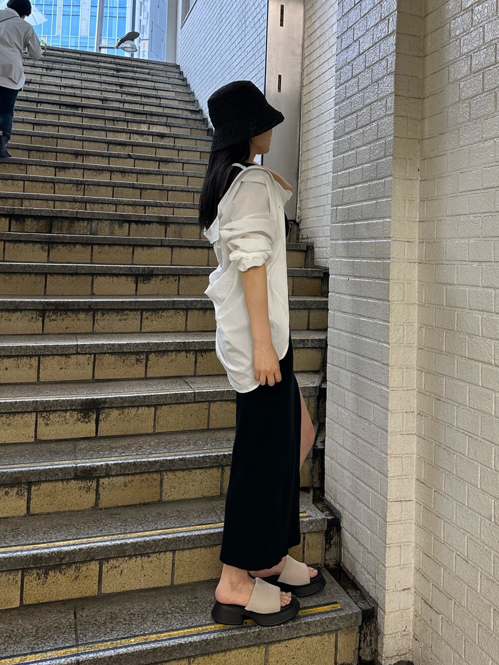 ブラック系のワンピース、ホワイト系のシャツ/ブラウス、ホワイト系のサンダルを着用したレディースの春コーディネートの2枚目の写真