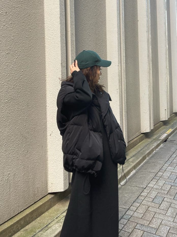 ブラック系のダウンベスト、ブラック系のワンピース、ブラック系のブーツを着用したレディースの秋コーディネートの4枚目の写真