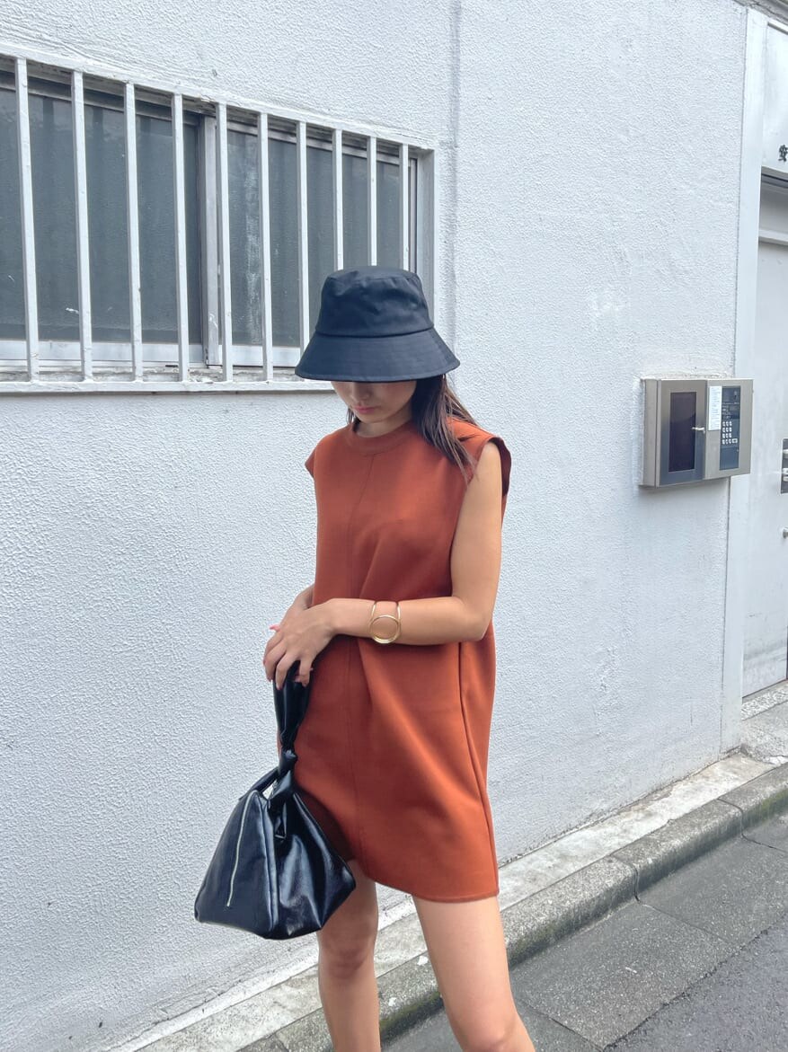 オレンジ系のワンピース、ブラック系のハンドバッグ、ブラック系のサンダルを着用したレディースの夏コーディネートの2枚目の写真