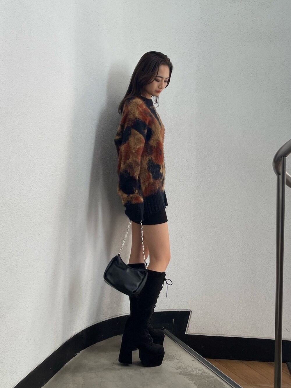 ブラック系のスカート、ブラック系のハンドバッグ、ブラック系のブーツを着用したレディースの秋コーディネートの2枚目の写真