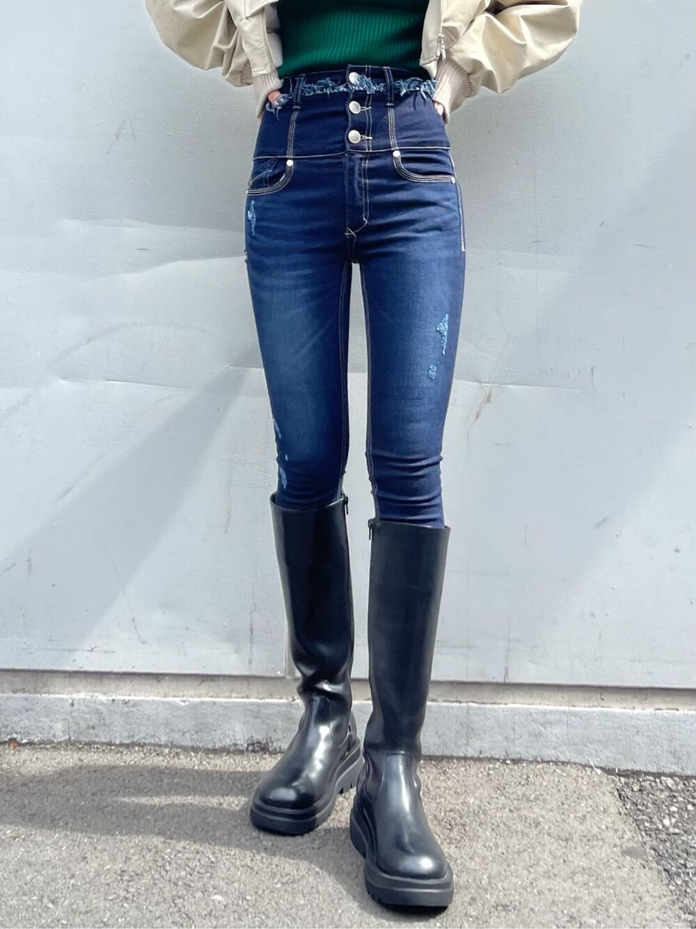 ホワイト系のブルゾン、ブラック系のブーツ、ブルー系のデニムパンツを着用したレディースの秋コーディネートの7枚目の写真