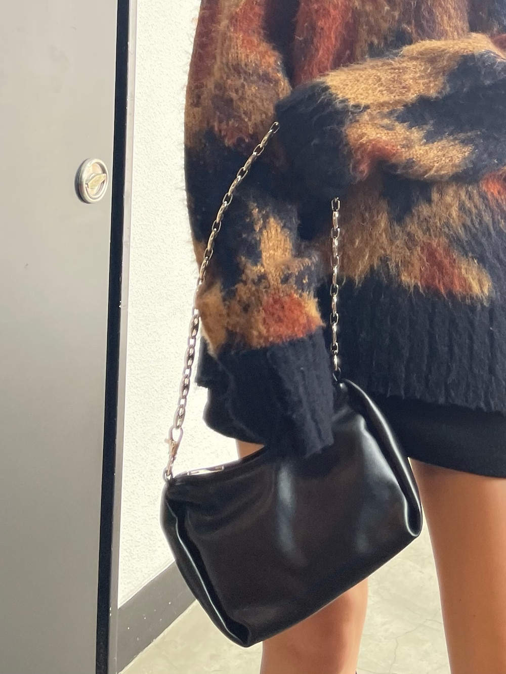 ブラック系のスカート、ブラック系のハンドバッグ、ブラック系のブーツを着用したレディースの秋コーディネートの5枚目の写真