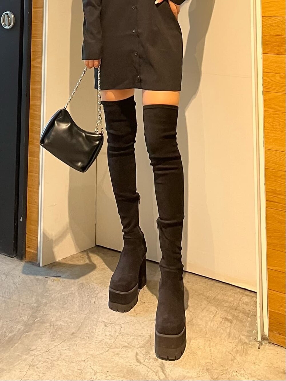 ブラック系のワンピース、ブラック系のブーツ、ブラック系のハンドバッグを着用したレディースの秋コーディネートの7枚目の写真