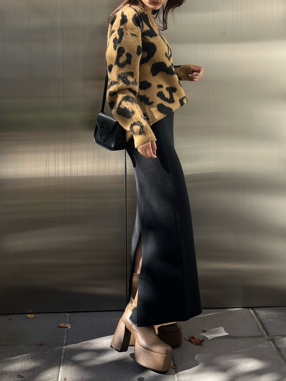 ベージュ系のニット/セーター、ブラウン系のブーツ、ブラック系のスカートを着用したレディースの秋コーディネートの2枚目の写真