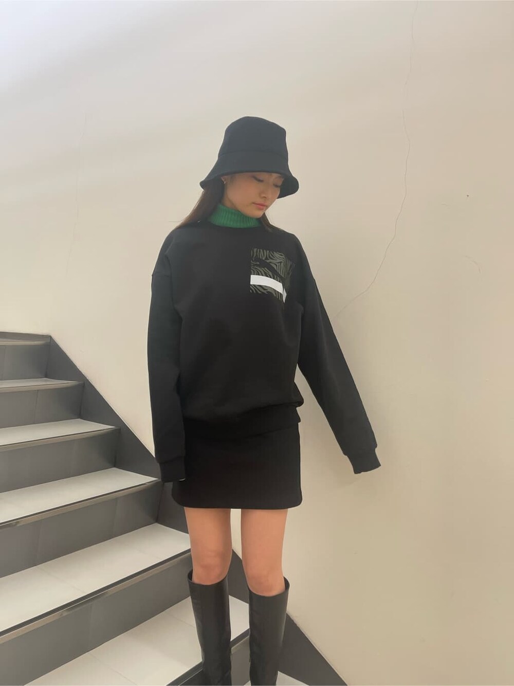 ブラック系のブーツ、ブラック系のTシャツ/カットソー、ブラック系のスカートを着用したレディースの冬コーディネートの2枚目の写真