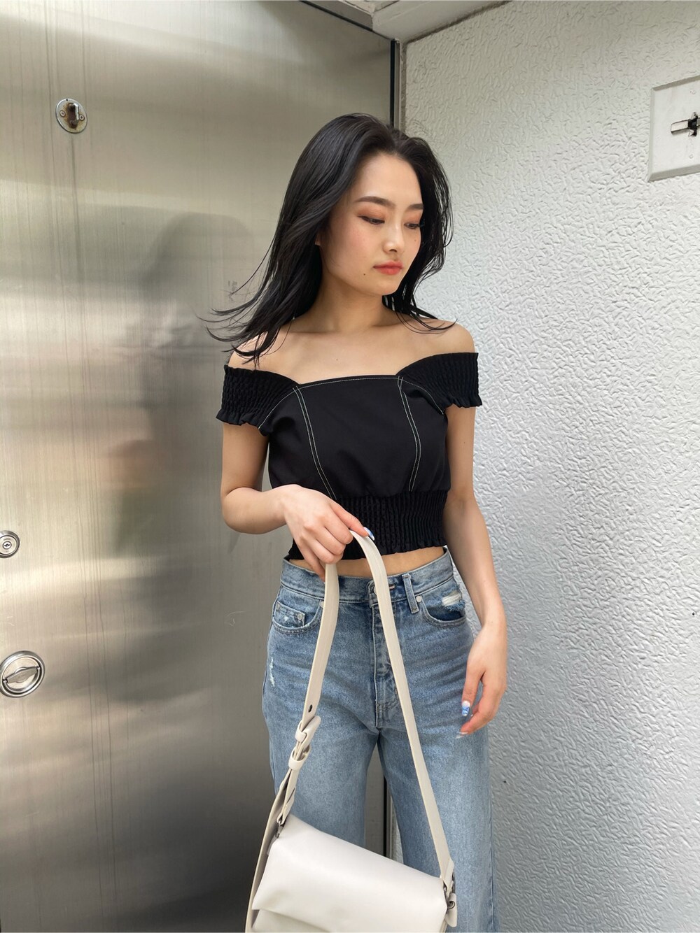 ホワイト系のショルダーバッグ、ブラック系のサンダル、ブルー系のデニムパンツを着用したレディースの春コーディネートの3枚目の写真