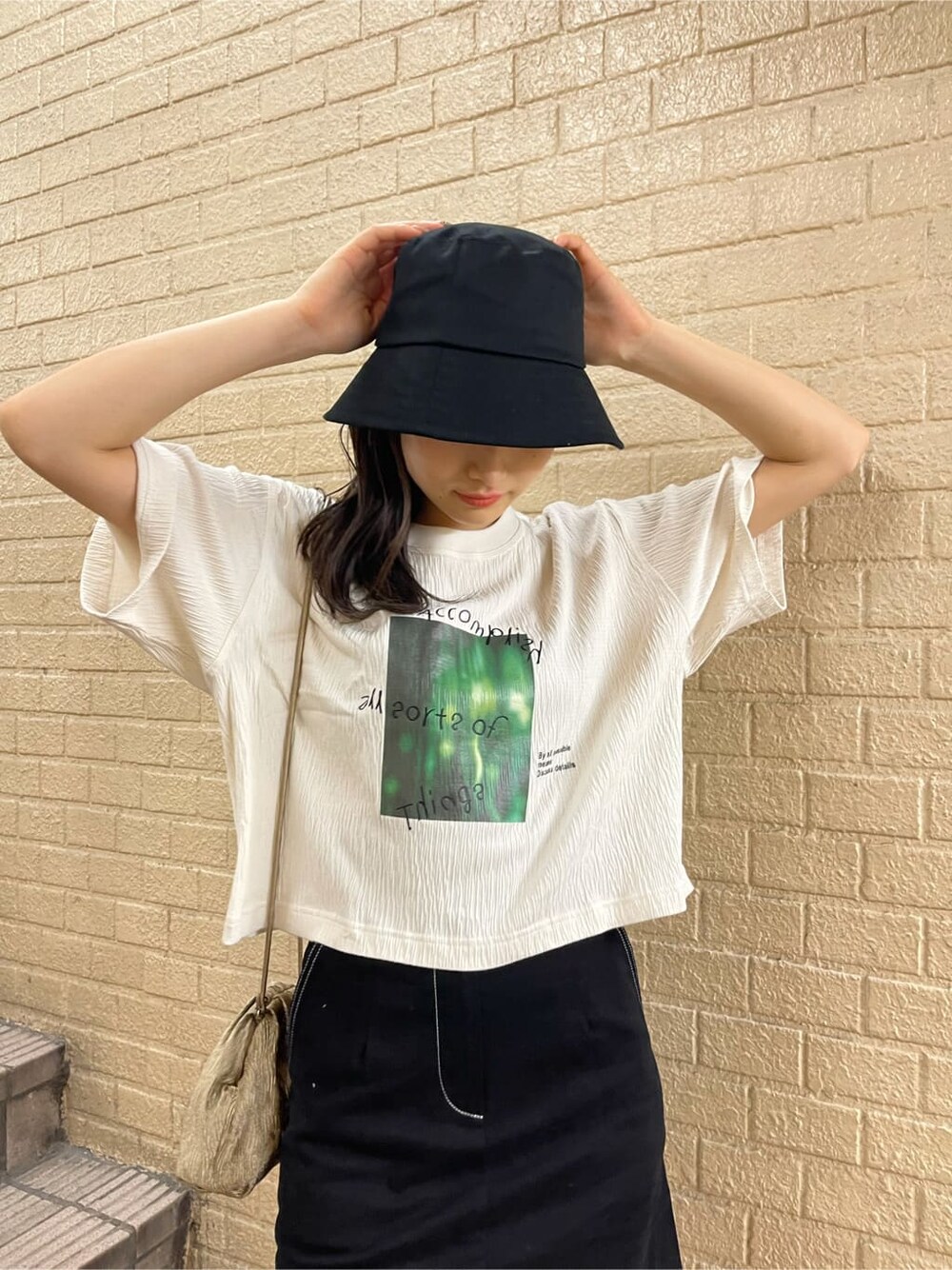 ベージュ系のハンドバッグ、ブラック系のスカート、ブラック系のサンダルを着用したレディースの夏コーディネートの3枚目の写真