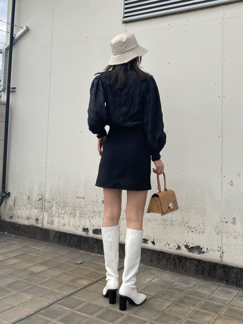 ホワイト系のブーツ、ブラウン系のハンドバッグ、ブラック系のシャツ/ブラウスを着用したレディースの春コーディネートの3枚目の写真