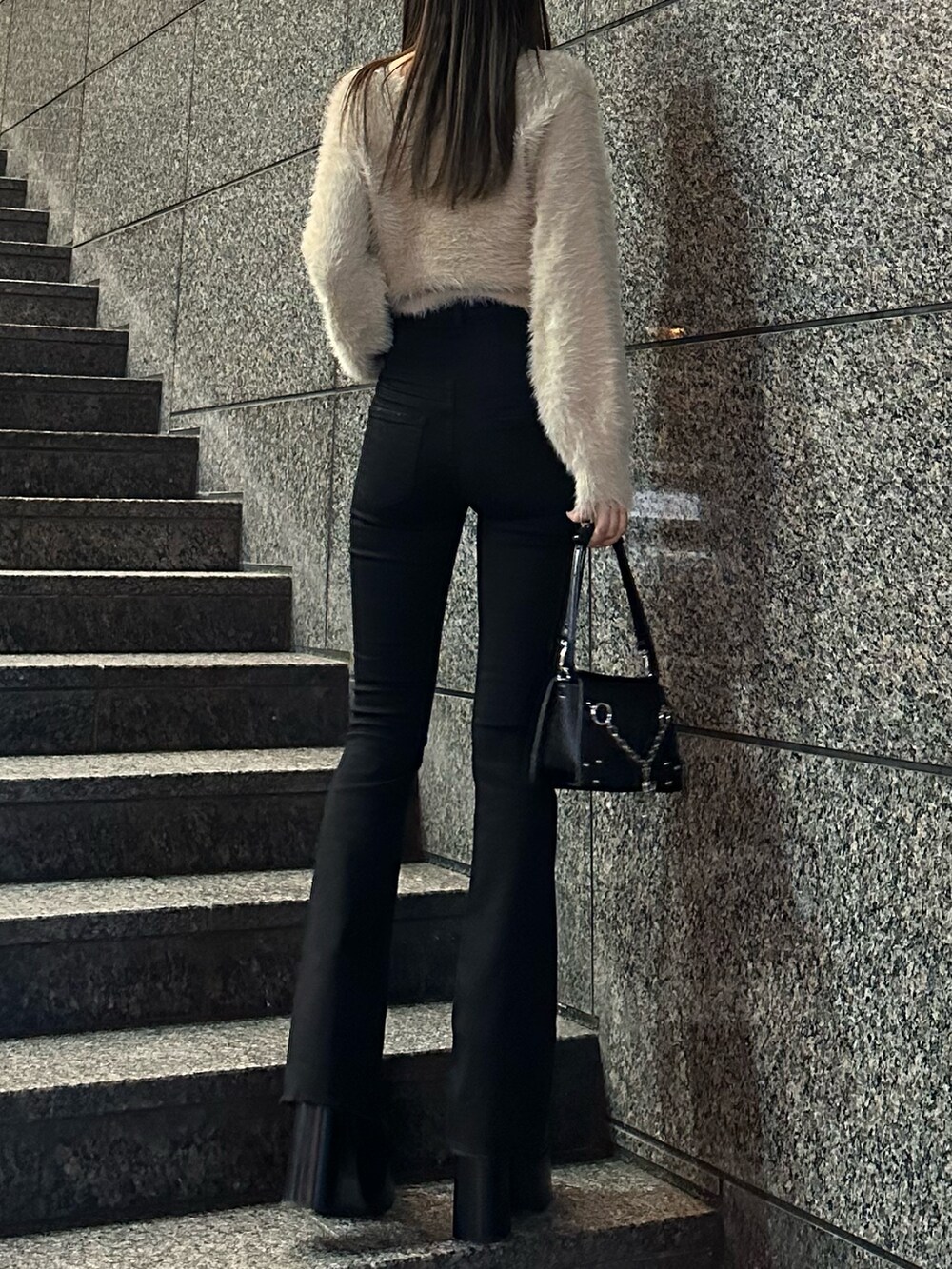 ブラック系のデニムパンツ、ベージュ系のニット/セーター、ブラック系のブーツを着用したレディースの冬コーディネートの2枚目の写真