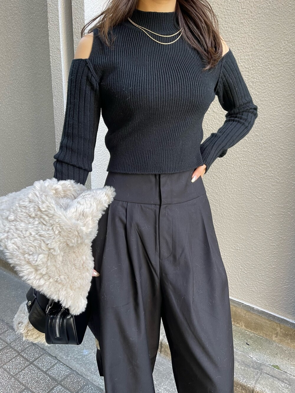 ブラック系のニット/セーター、ブラック系のその他パンツ、ブラック系のハンドバッグを着用したレディースの冬コーディネートの7枚目の写真