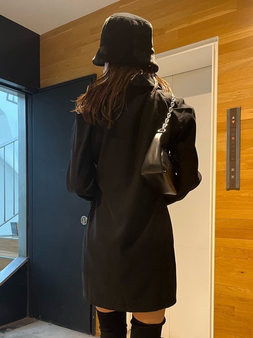 ブラック系のワンピース、ブラック系のブーツ、ブラック系のハンドバッグを着用したレディースの秋コーディネートの6枚目の写真