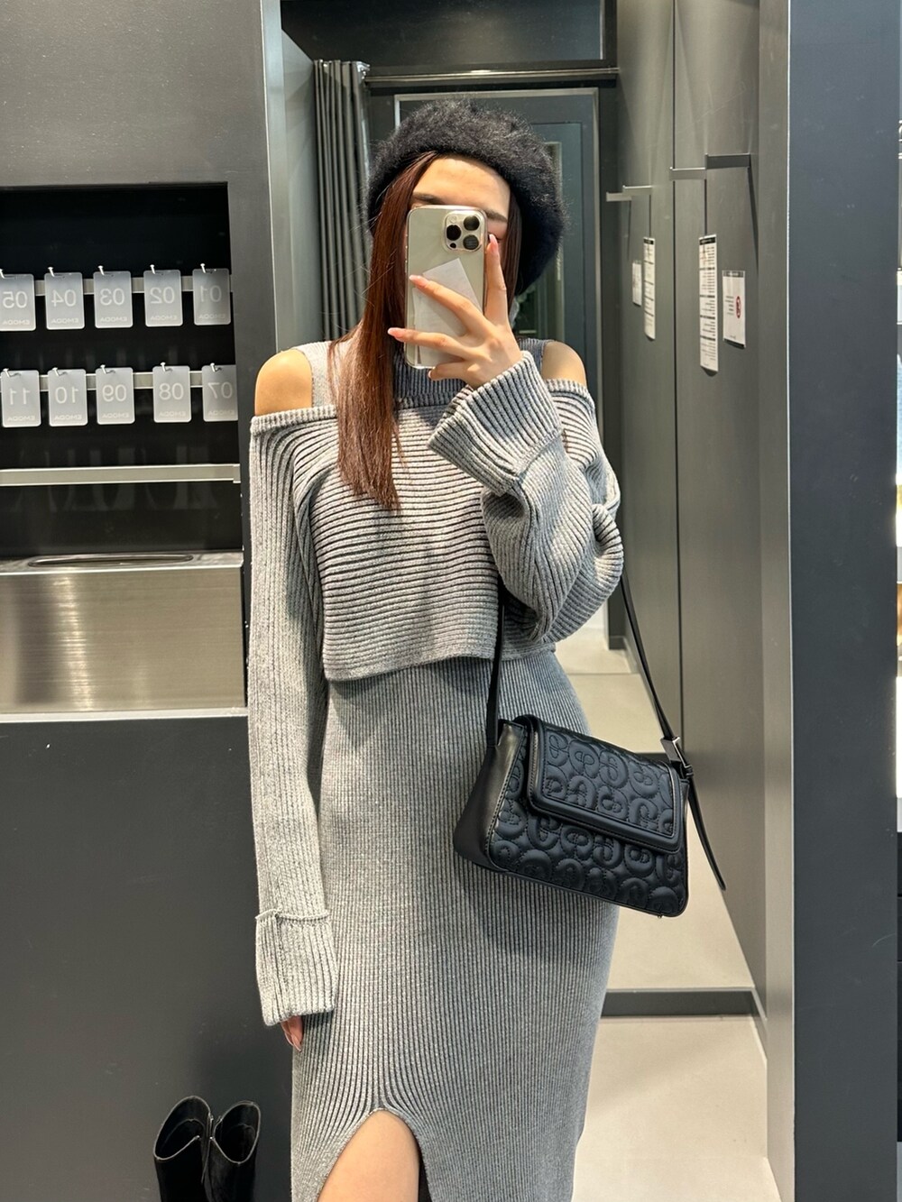 グレー系のワンピース、ブラック系のブーツ、ブラック系のハンドバッグを着用したレディースの冬コーディネートの5枚目の写真