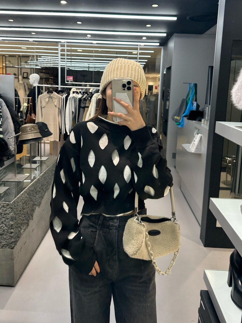 ブラック系のデニムパンツ、ホワイト系のハンドバッグ、ブラック系のローファーを着用したレディースの冬コーディネートの4枚目の写真