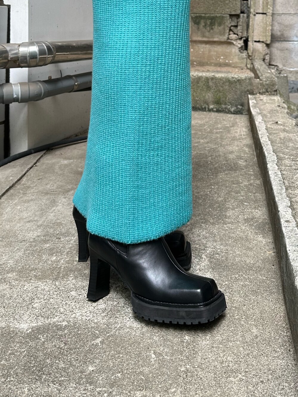 ブラック系のハンドバッグ、ブラック系のブーツ、ブルー系のスカートを着用したレディースの秋コーディネートの8枚目の写真