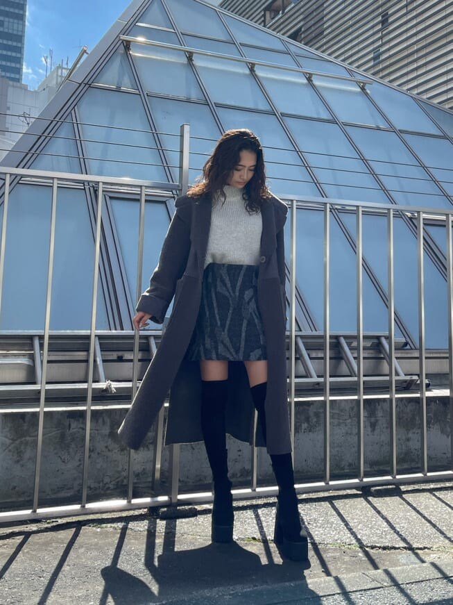 ブラック系のブーツ、ホワイト系のニット/セーター、その他のスカートを着用したレディースの秋コーディネートの2枚目の写真