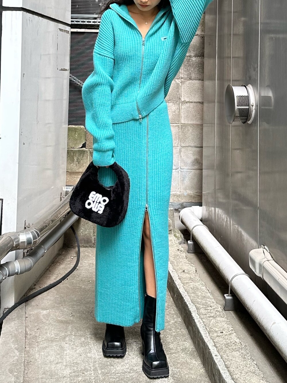 ブラック系のハンドバッグ、ブラック系のブーツ、ブルー系のスカートを着用したレディースの秋コーディネートの2枚目の写真