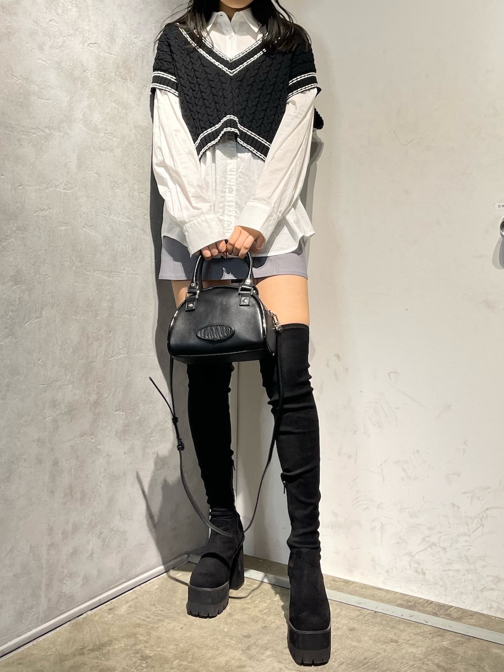 ブラック系のブーツ、ブラック系のベスト、ホワイト系のシャツ/ブラウスを着用したレディースの冬コーディネートの2枚目の写真