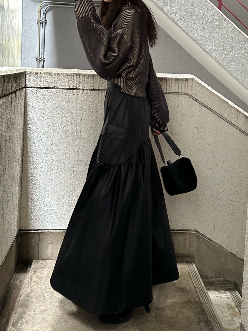 ブラック系のスカート、ブラック系のニット/セーター、ブラック系のハンドバッグを着用したレディースの秋コーディネートの4枚目の写真