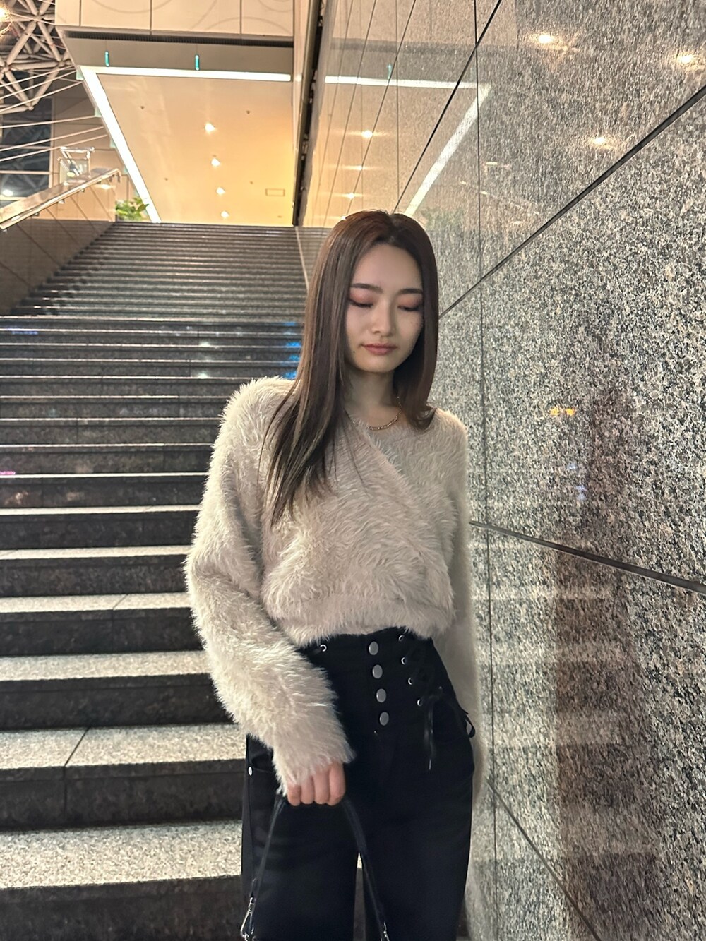 ブラック系のデニムパンツ、ベージュ系のニット/セーター、ブラック系のブーツを着用したレディースの冬コーディネートの3枚目の写真