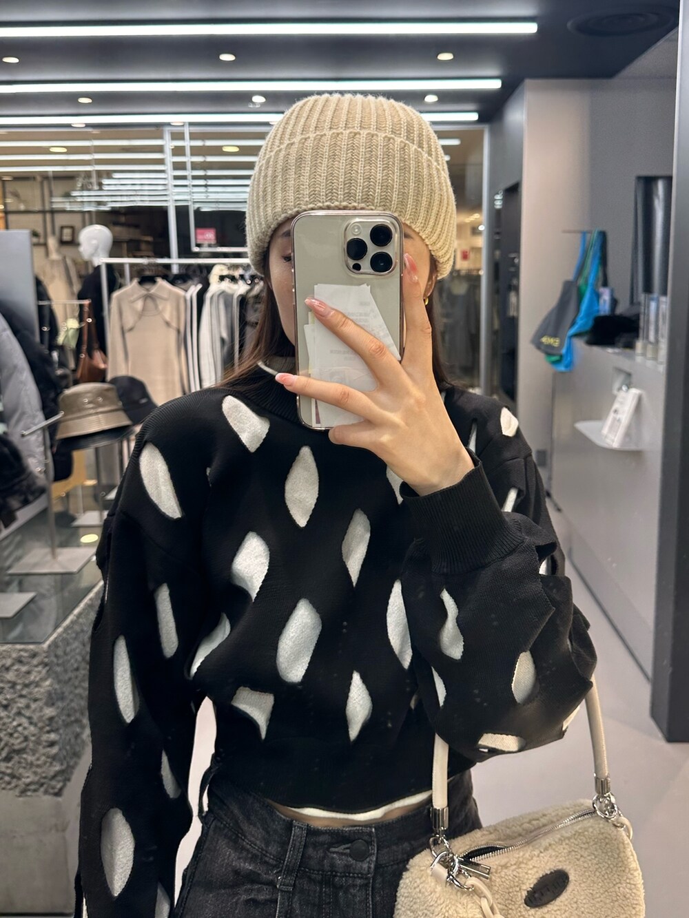 ブラック系のデニムパンツ、ホワイト系のハンドバッグ、ブラック系のローファーを着用したレディースの冬コーディネートの5枚目の写真