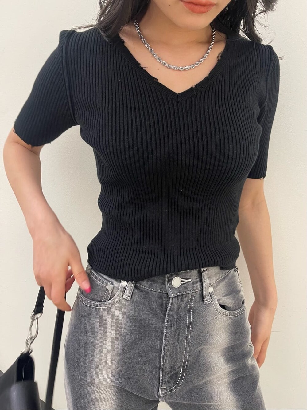 ブラック系のサンダル、ブラック系のハンドバッグ、ブラック系のデニムパンツを着用したレディースの春コーディネートの6枚目の写真