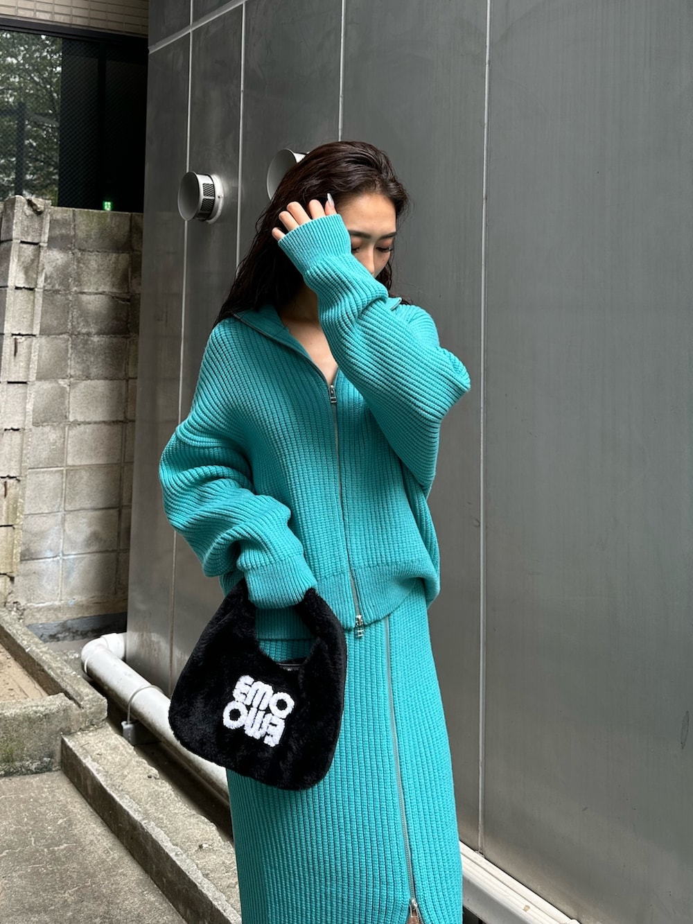 ブラック系のハンドバッグ、ブラック系のブーツ、ブルー系のスカートを着用したレディースの秋コーディネートの5枚目の写真