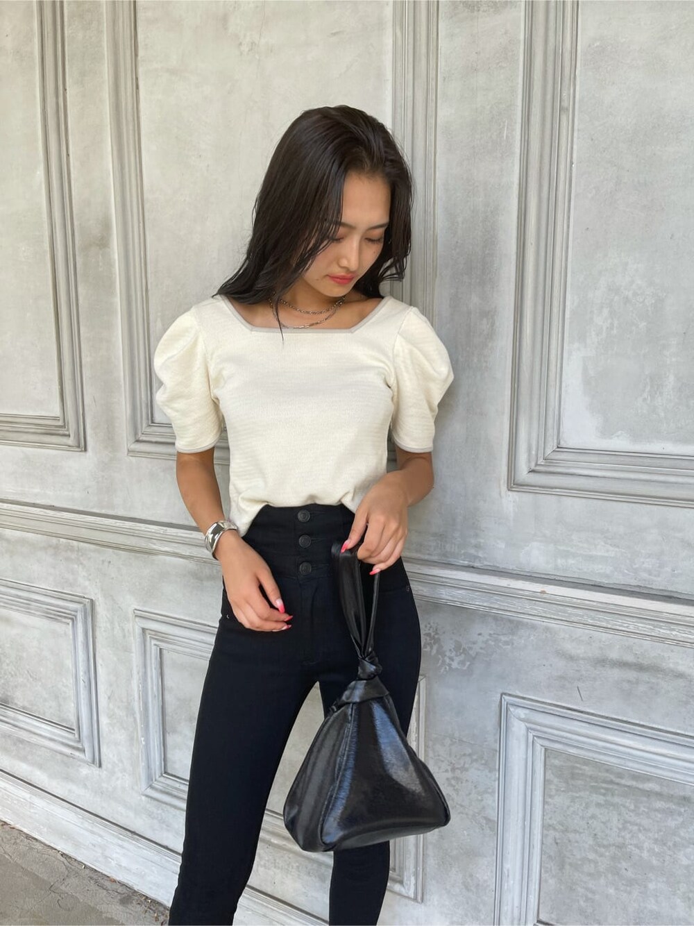 ブラック系のハンドバッグ、ブラウン系のサンダル、ホワイト系のTシャツ/カットソーを着用したレディースの夏コーディネートの2枚目の写真