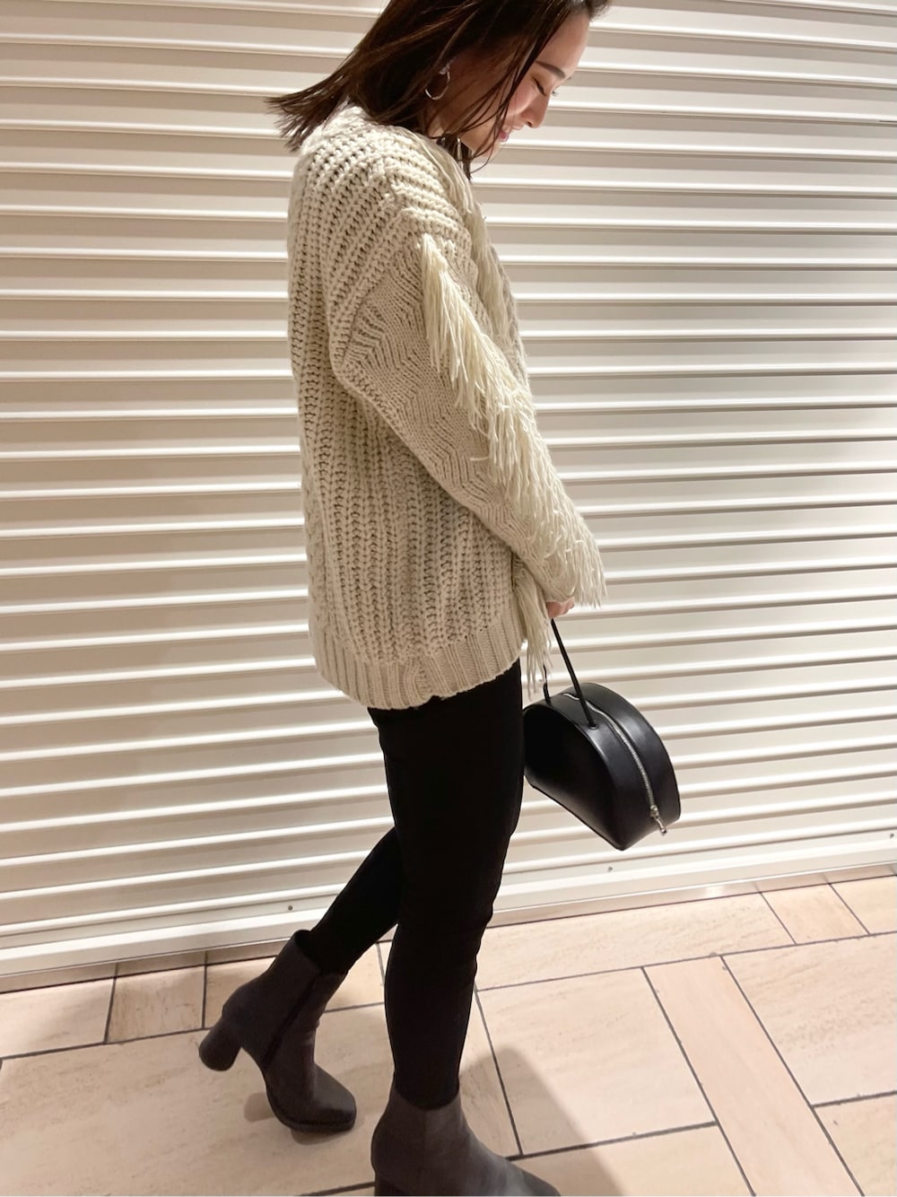 ブラック系のショルダーバッグ、ブラック系のブーツ、グレー系のデニムパンツを着用したレディースの冬コーディネートの2枚目の写真