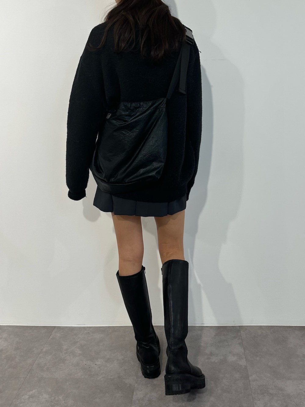 ブラック系のニット/セーター、グレー系のスカート、ブラック系のブーツを着用したレディースの冬コーディネートの3枚目の写真