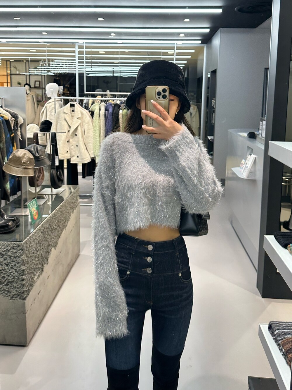 グレー系のニット/セーター、ブルー系のデニムパンツ、ブラック系のハンドバッグを着用したレディースの秋コーディネートの4枚目の写真