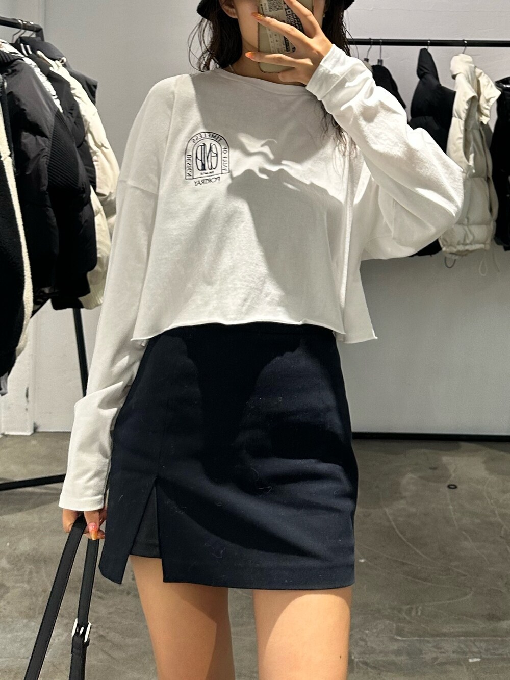 ブラック系のブーツ、ブラック系のスカート、ホワイト系のTシャツ/カットソーを着用したレディースの秋コーディネートの5枚目の写真