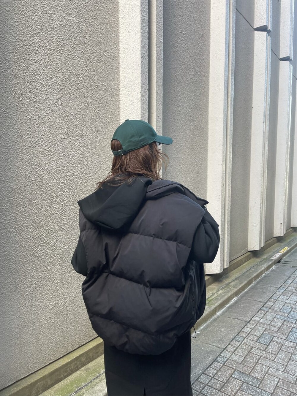 ブラック系のダウンベスト、ブラック系のワンピース、ブラック系のブーツを着用したレディースの秋コーディネートの7枚目の写真