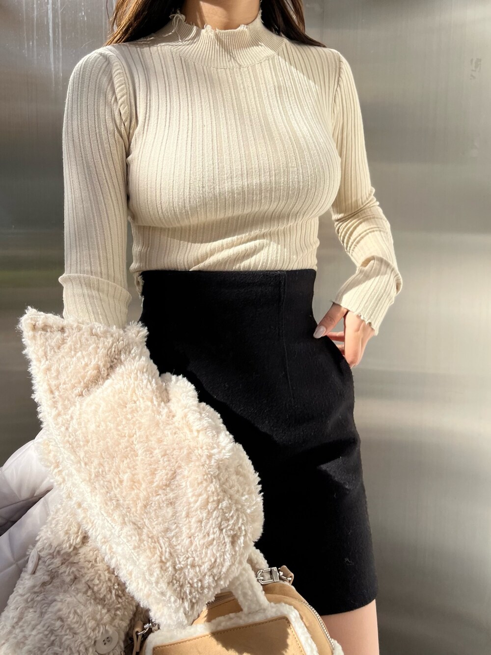 ホワイト系のブルゾン、ベージュ系のハンドバッグ、ブラウン系のブーツを着用したレディースの冬コーディネートの5枚目の写真