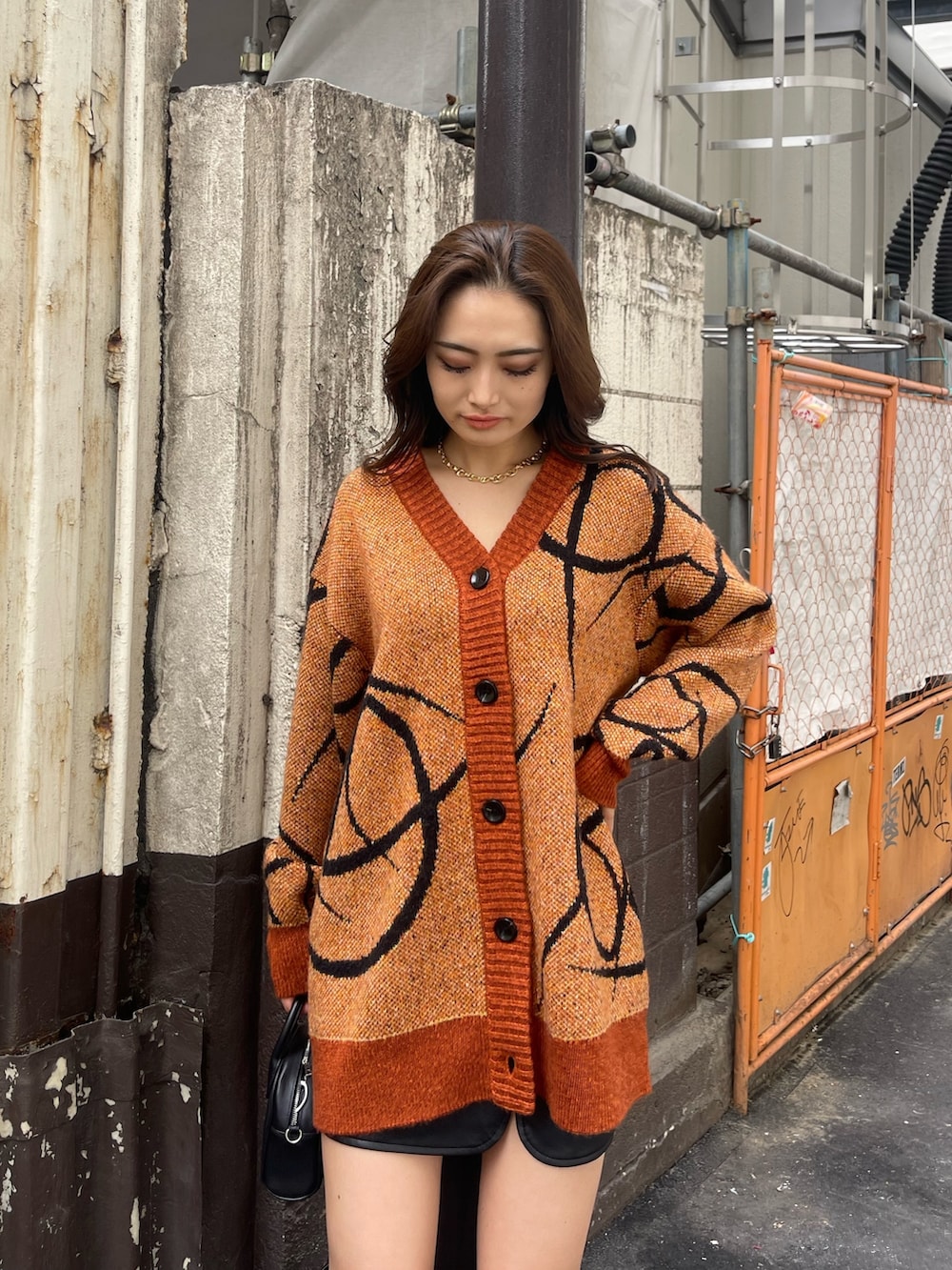 オレンジ系のニット/セーター、ブラック系のハンドバッグ、ブラック系のブーツを着用したレディースの秋コーディネートの3枚目の写真