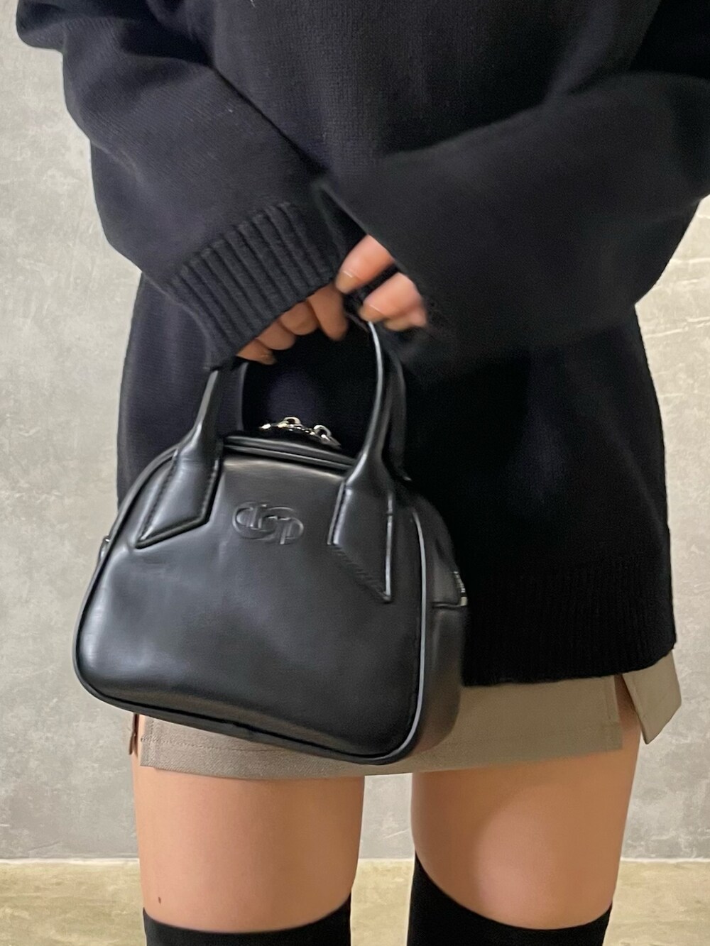 ブラック系のニット/セーター、ベージュ系のスカート、ブラック系のブーツを着用したレディースの冬コーディネートの6枚目の写真