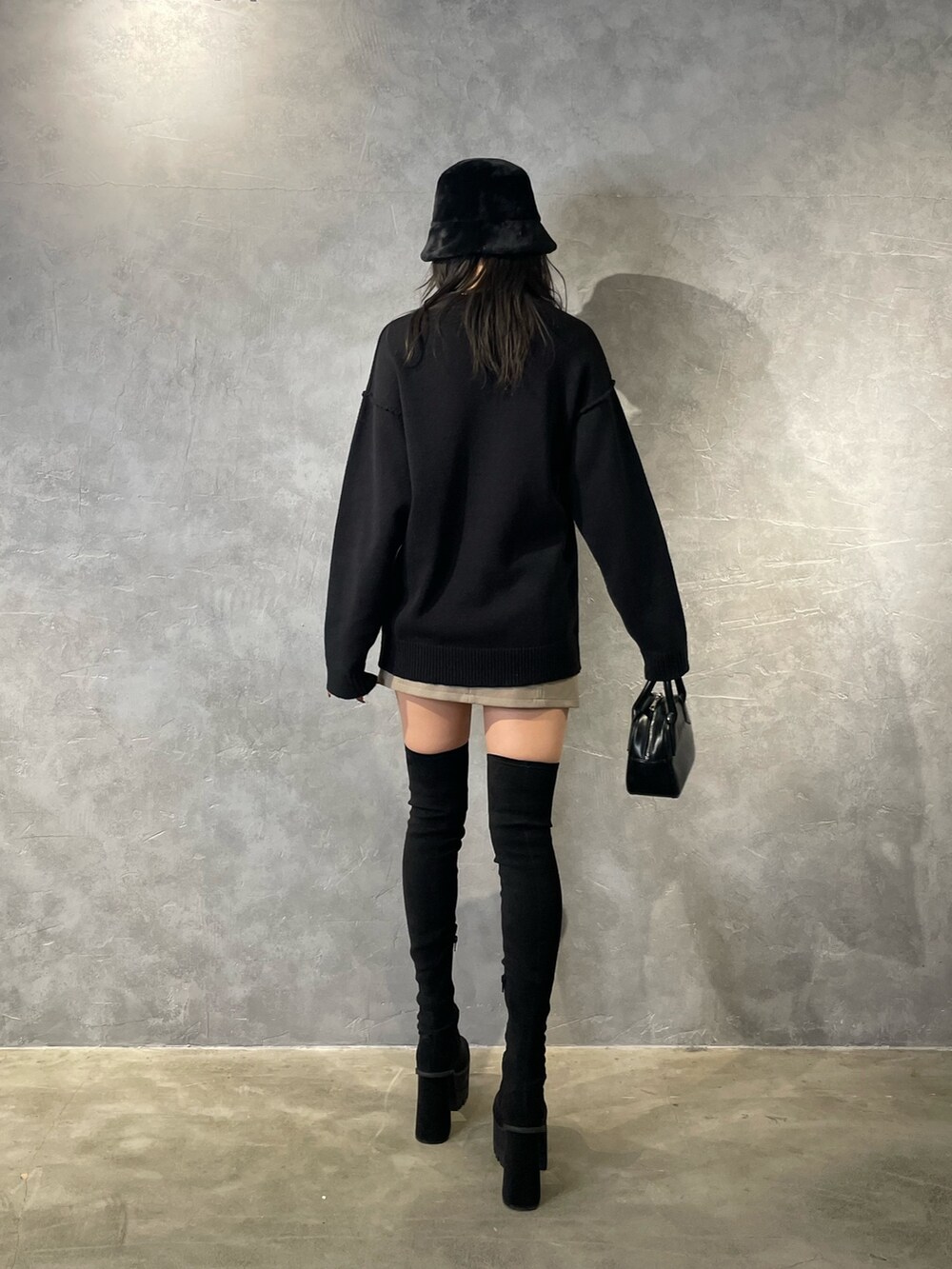 ブラック系のニット/セーター、ベージュ系のスカート、ブラック系のブーツを着用したレディースの冬コーディネートの4枚目の写真