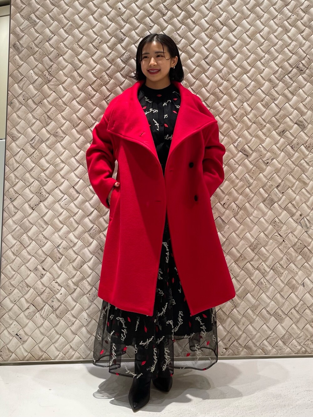 レッド系のその他アウター、ブラック系のスカート、ブラック系のカーディガン/ボレロを着用したレディースの冬コーディネートの2枚目の写真