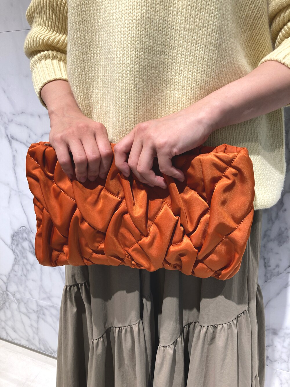 イエロー系のニット/セーター、オレンジ系のショルダーバッグ、グリーン系のスカートを着用したレディースの秋コーディネートの5枚目の写真