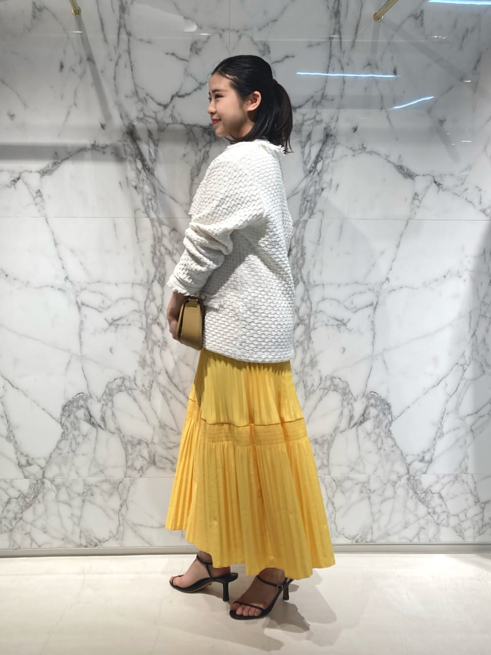 ベージュ系のショルダーバッグ、ホワイト系のカーディガン/ボレロ、ホワイト系のTシャツ/カットソーを着用したレディースの春コーディネートの2枚目の写真