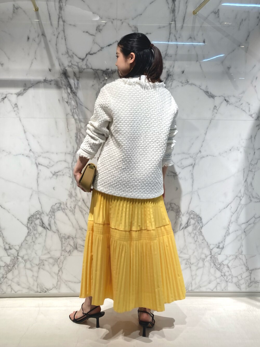 ベージュ系のショルダーバッグ、ホワイト系のカーディガン/ボレロ、ホワイト系のTシャツ/カットソーを着用したレディースの春コーディネートの3枚目の写真