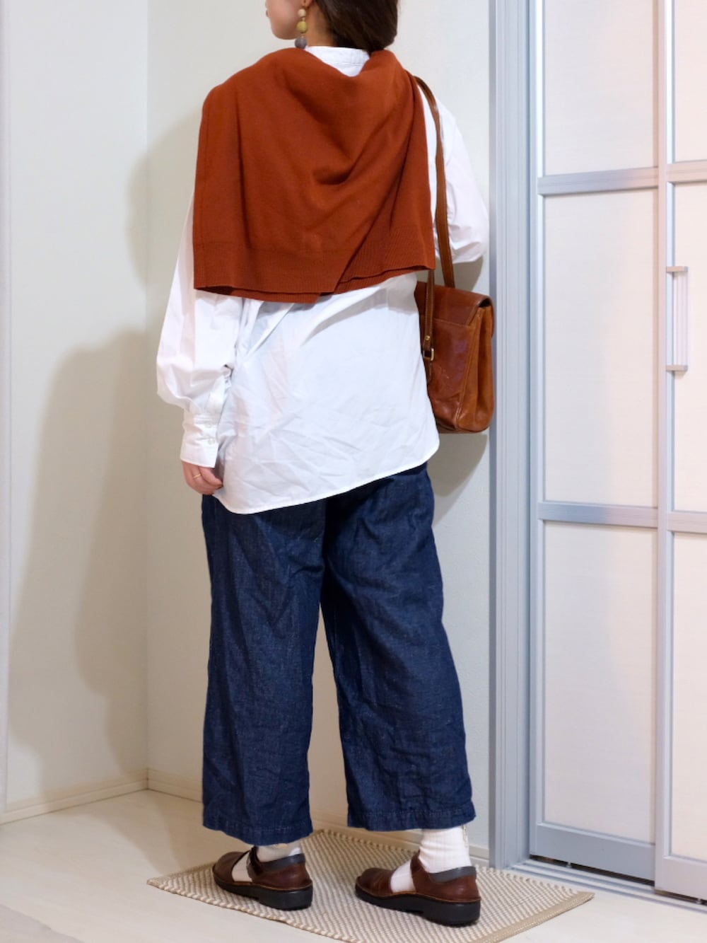 ブルー系のデニムパンツ、ホワイト系のシャツ/ブラウス、レッド系のニット/セーターを着用したレディースの秋コーディネートの2枚目の写真