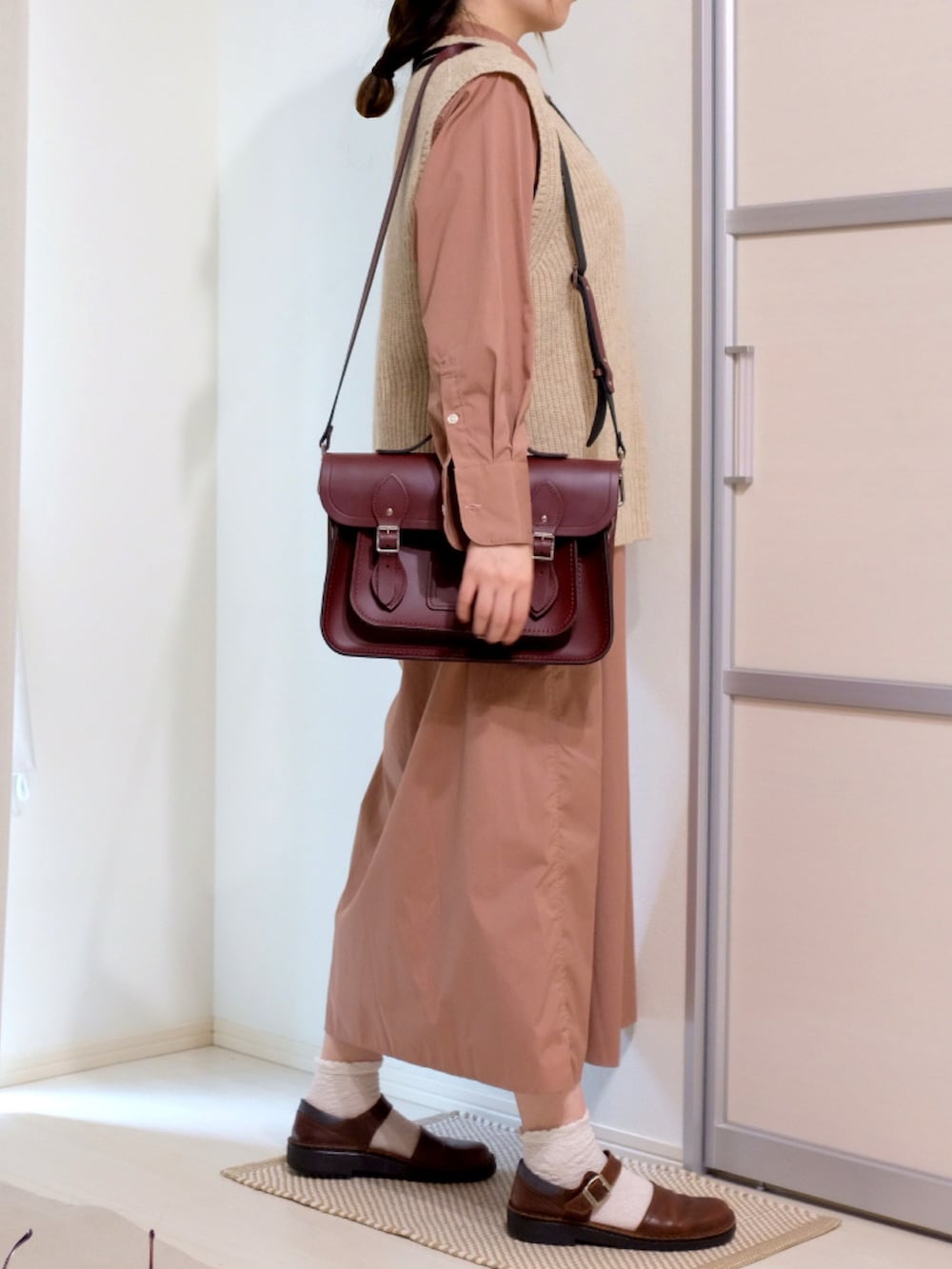 ベージュ系のベスト、ピンク系のシャツワンピース、レッド系のショルダーバッグを着用したレディースの秋コーディネートの2枚目の写真