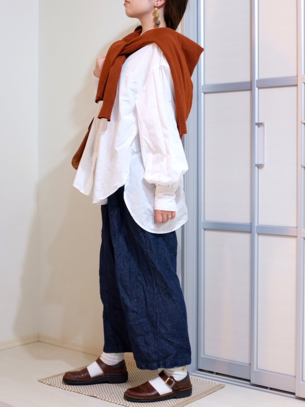 ブルー系のデニムパンツ、ホワイト系のシャツ/ブラウス、レッド系のニット/セーターを着用したレディースの秋コーディネートの3枚目の写真