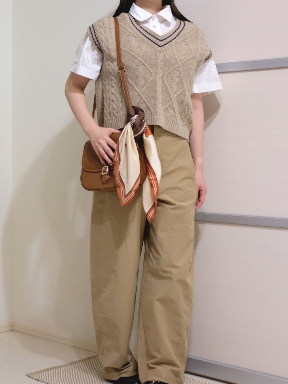 ホワイト系のシャツ/ブラウス、ブラウン系のショルダーバッグ、ベージュ系のベストを着用したレディースの秋コーディネートの3枚目の写真