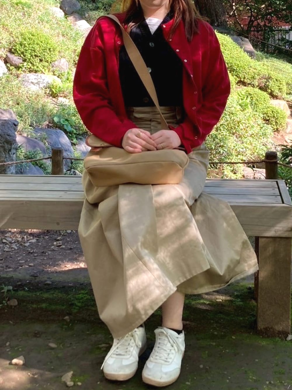 レッド系のカーディガン/ボレロ、ベージュ系のショルダーバッグ、ベージュ系のスカートを着用したレディースの秋コーディネートの2枚目の写真