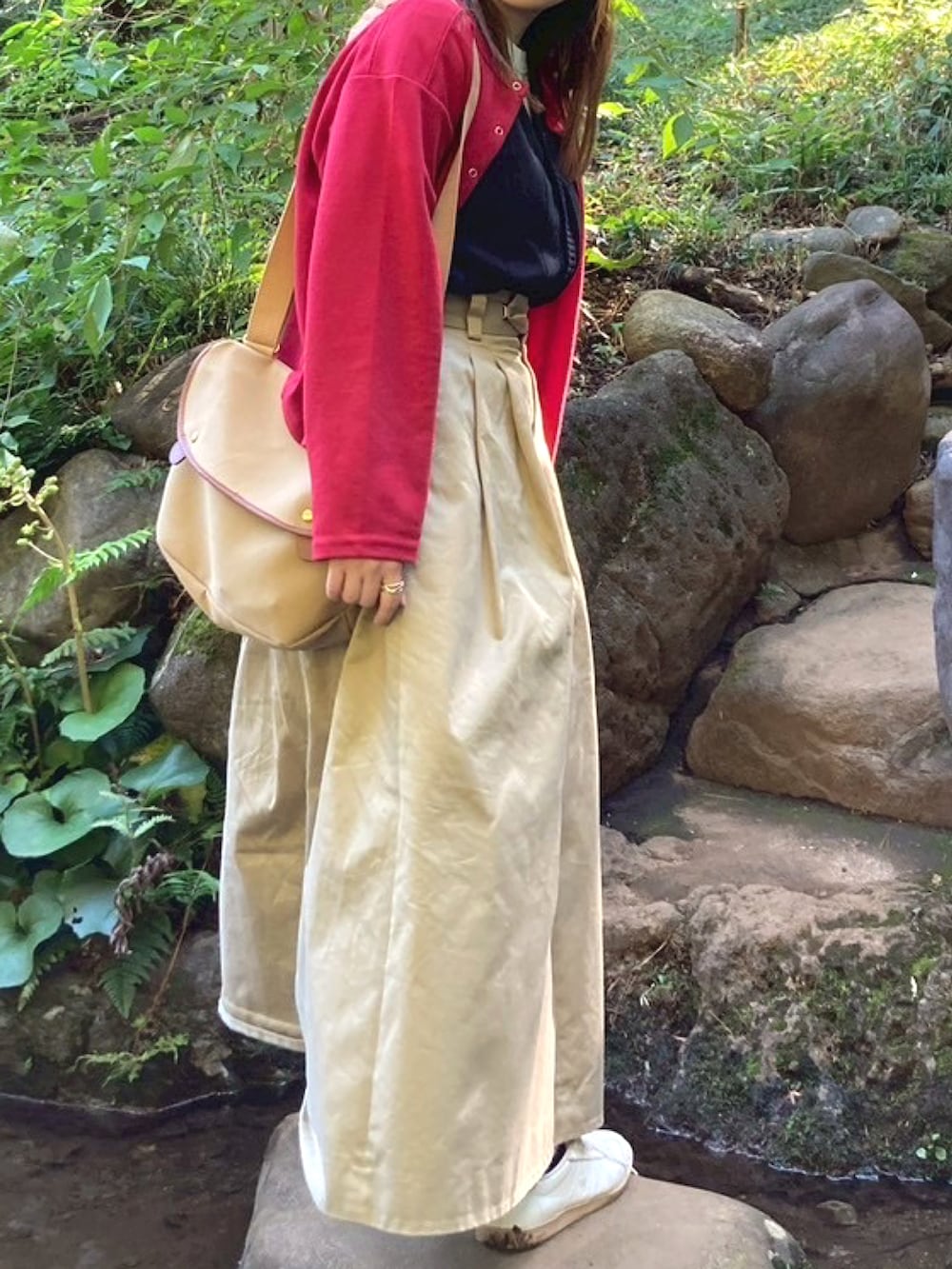 レッド系のカーディガン/ボレロ、ベージュ系のショルダーバッグ、ベージュ系のスカートを着用したレディースの秋コーディネートの3枚目の写真