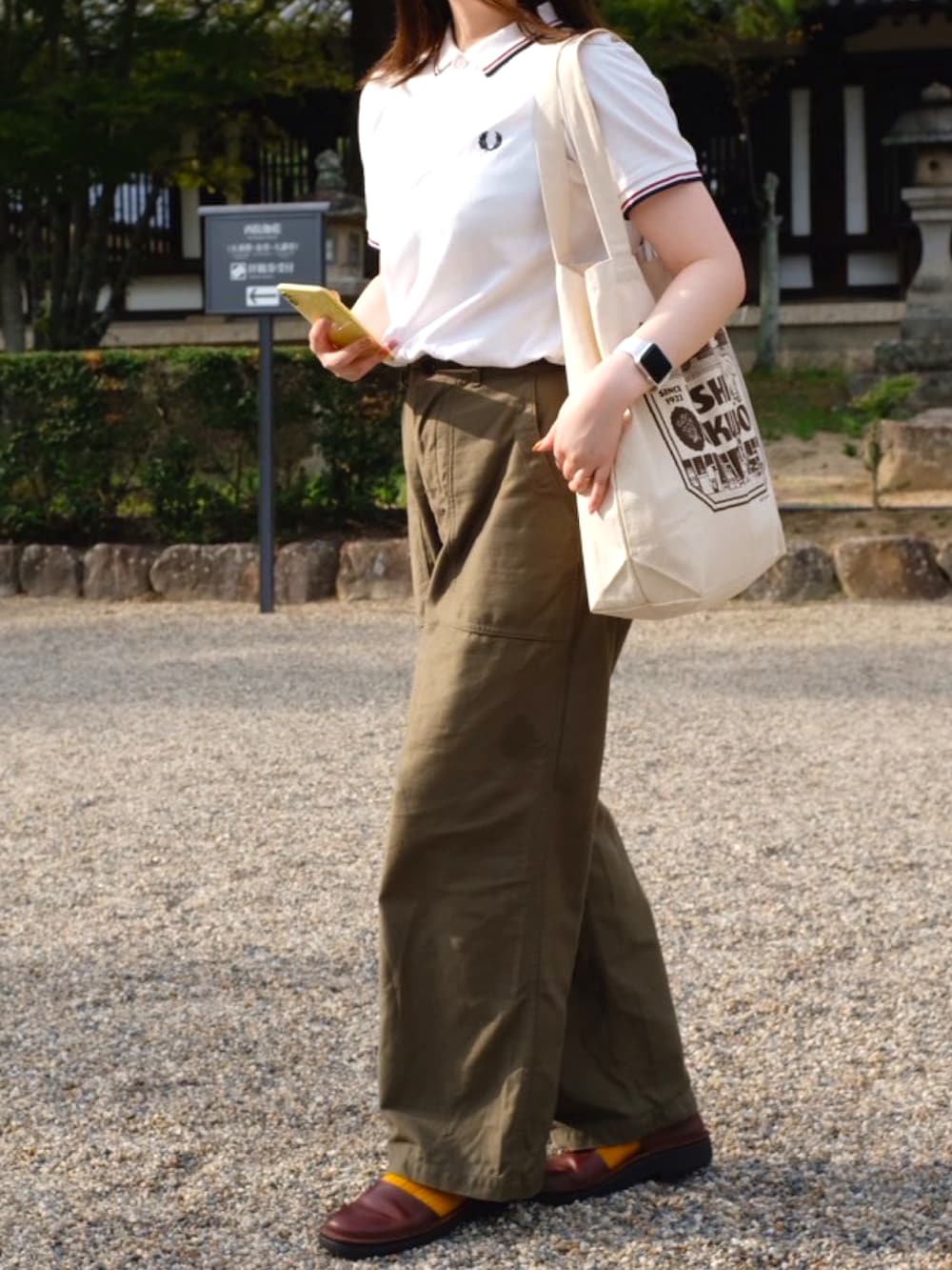 ホワイト系のポロシャツ、グリーン系のその他パンツ、ブラウン系のサンダルを着用したレディースの秋コーディネートの3枚目の写真