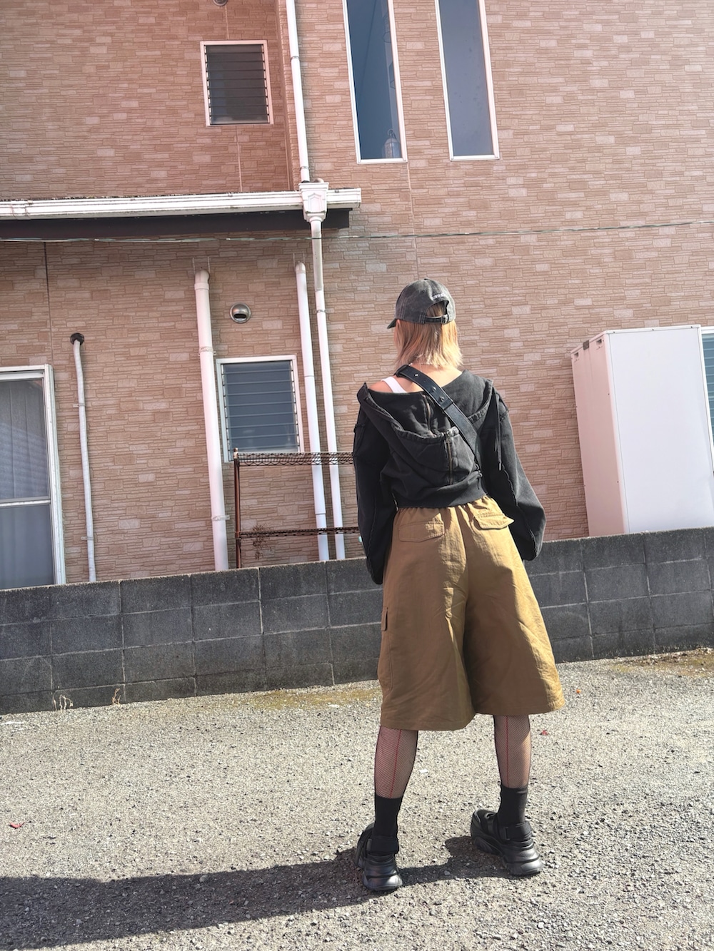 ベージュ系のパンツ、ブラック系のパーカー、ブラック系のショルダーバッグを着用したレディースの春コーディネートの3枚目の写真