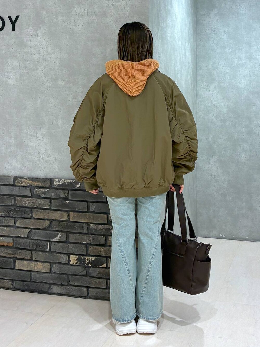 ホワイト系のスニーカー、ブルー系のデニムパンツ、ブラウン系のボストンバッグを着用したレディースの冬コーディネートの4枚目の写真