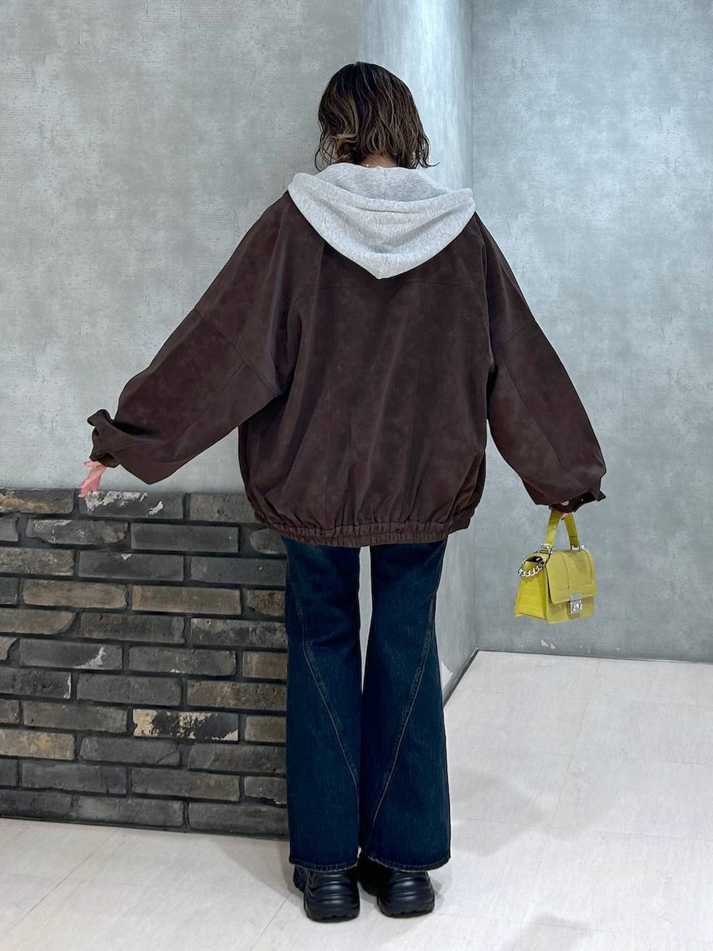 グレー系のスニーカー、ブルー系のデニムパンツ、イエロー系のハンドバッグを着用したレディースの秋コーディネートの5枚目の写真